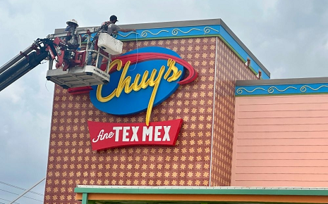Workers install signage at Bastrop’s first Chuy’s ahead of the restaurant’s planned May 18 opening at Sendero. Image by Amanda Cutshall of Community Impact