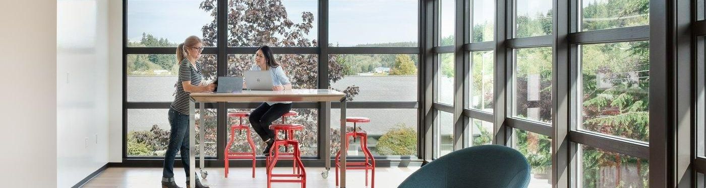 two women with laptops at high top table in modern office building space