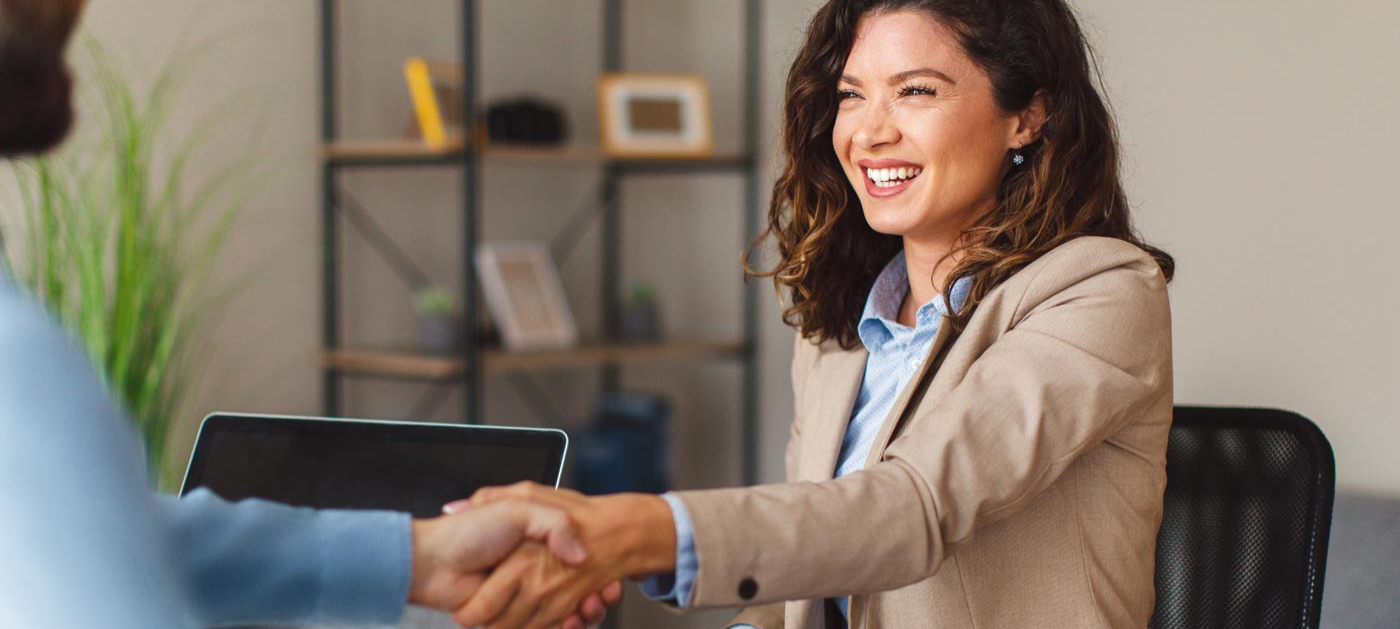smiling woman shaking hands with a business associate