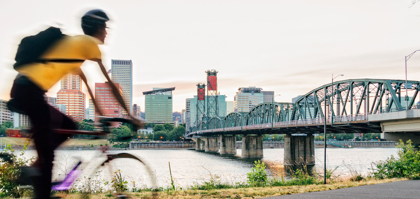 Young person biking along the Portland Oregon waterfront at sunset.