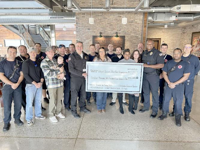 City of Beloit firefighters and police officers join Fire Chief Daniel Pease and Police Chief Andre Sayles in accepting a check for $55,000 which was raised in the Hendricks Commercial Properties golf outing “Backing the Badge.”  Photo provided