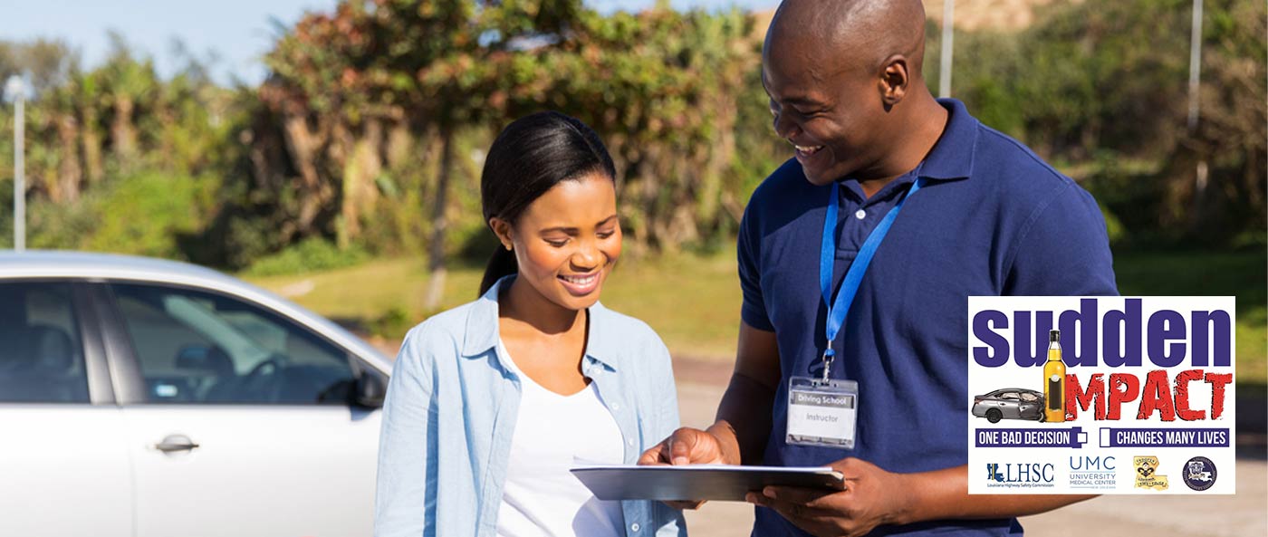 student and teacher looking over clipboard next to car