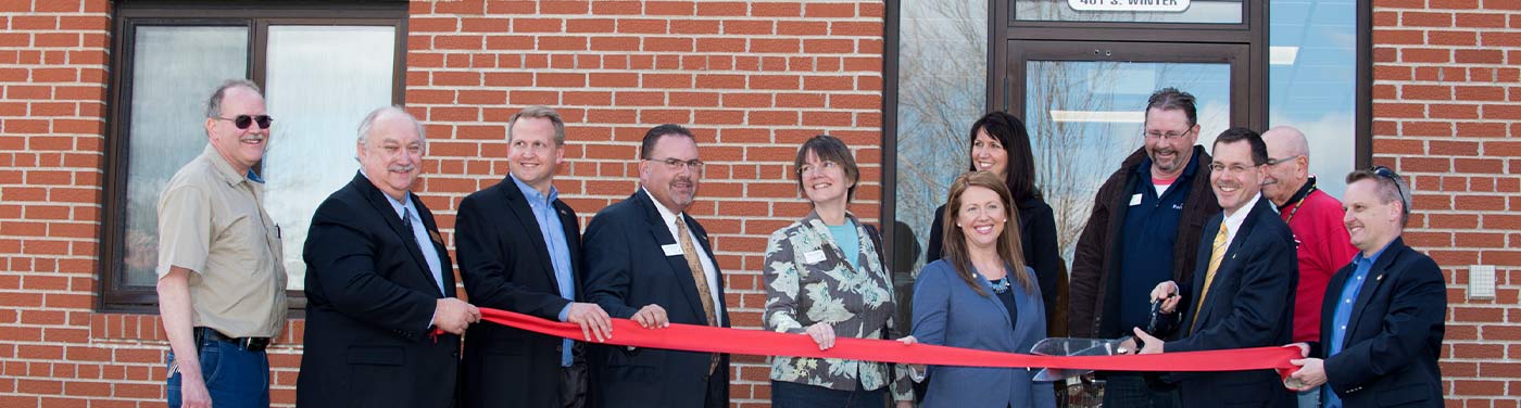 ribbon cutting ceremony outside red brick building