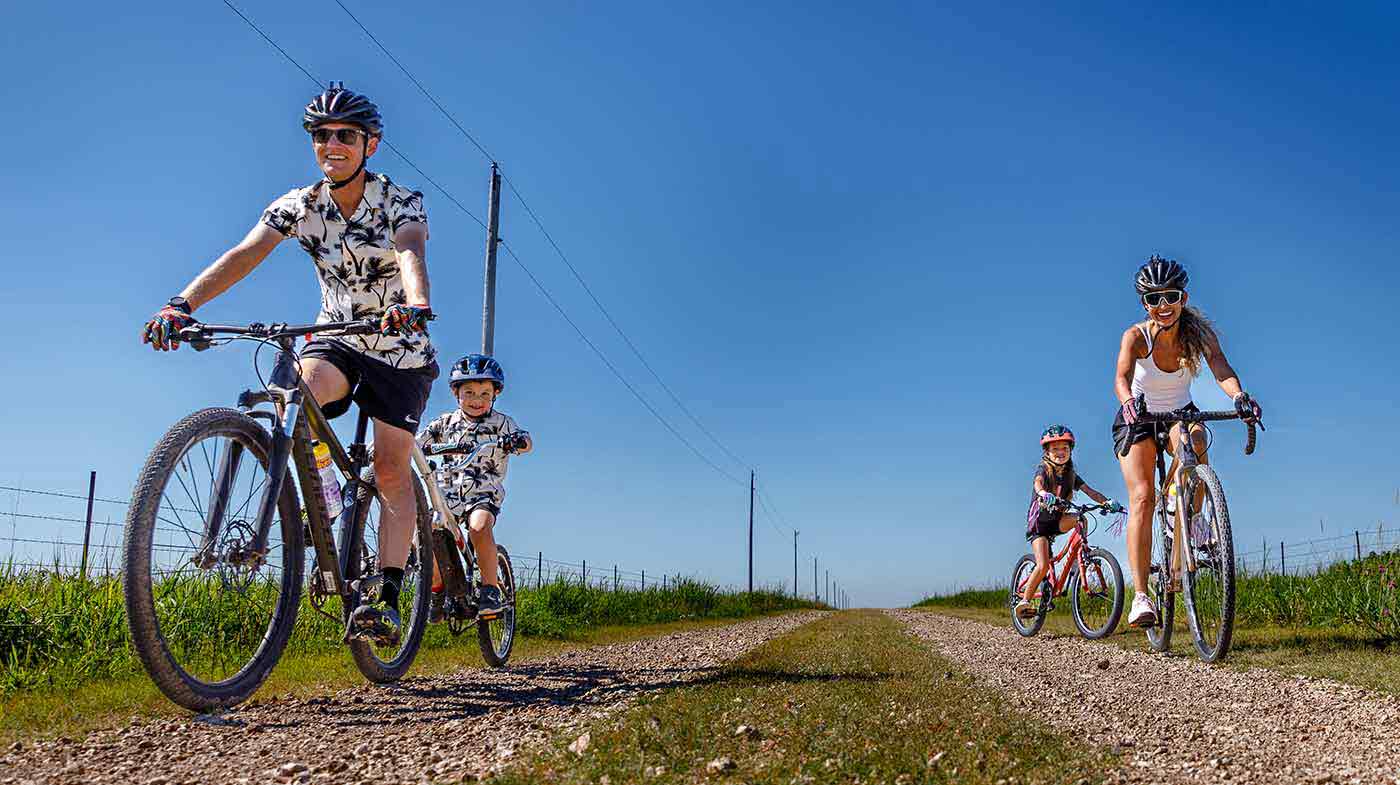 family riding bikes on dirt country road