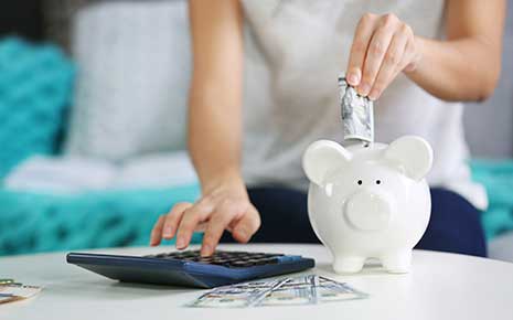 Woman adding cash to a piggy bank