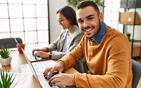 two hispanic employees working on laptops