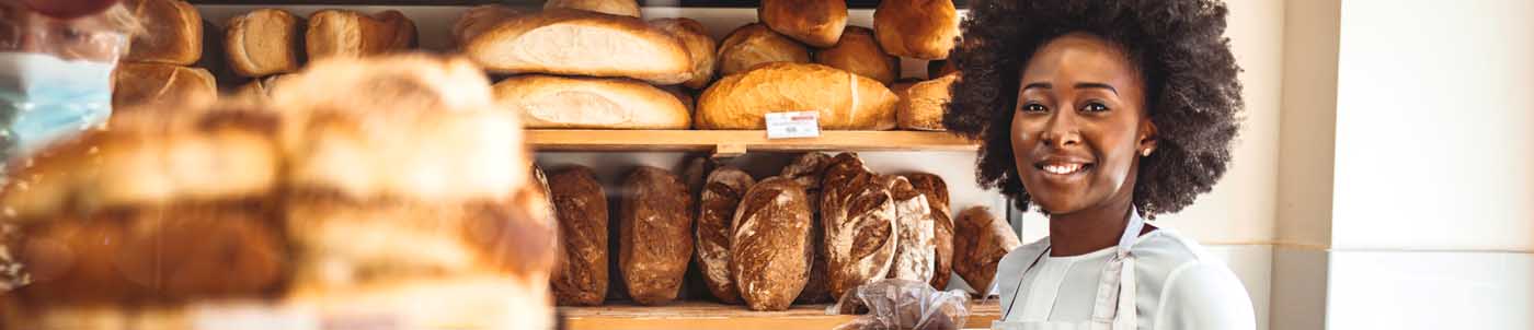 female baker standing among shelves of fresh bread