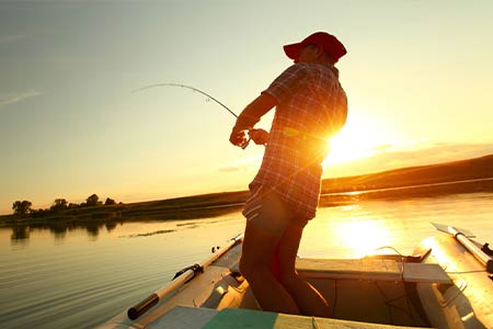 fisherman pulling in fish at sunset on boat