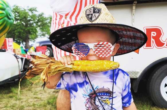 little boy in patriotic outfit eating corn on the cob