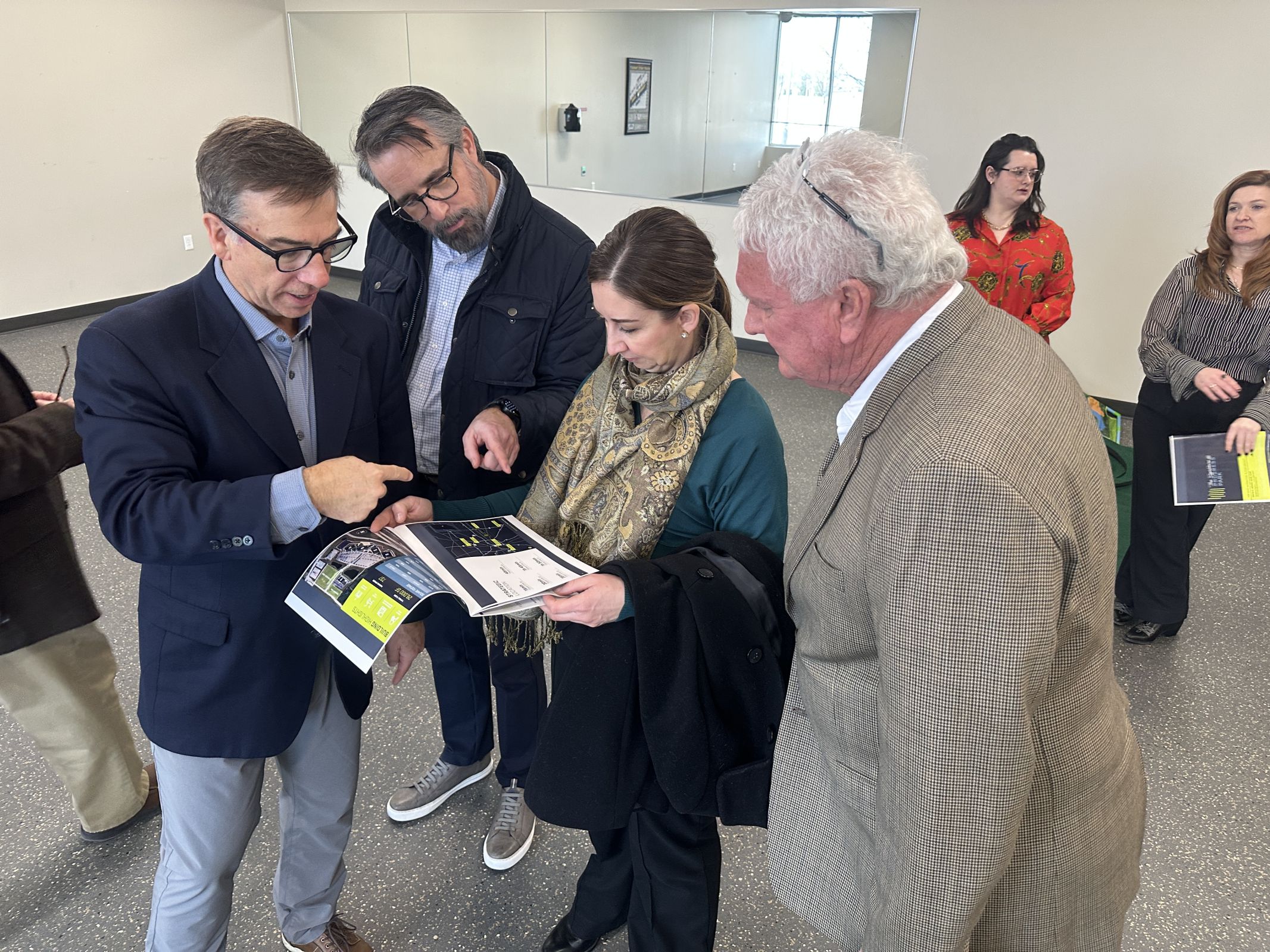 From left, David Moore of Cushman & Wakefield, Jason Hester and Nicole Nemeth of the Indy Partnership, and Greenfield Mayor Guy Titus look at the brochure for The Signature @ Progress Park while Victoria Ross-Frost of the Indiana Municipal Power Agency and Erica Adams of the HEDC converse in the background.