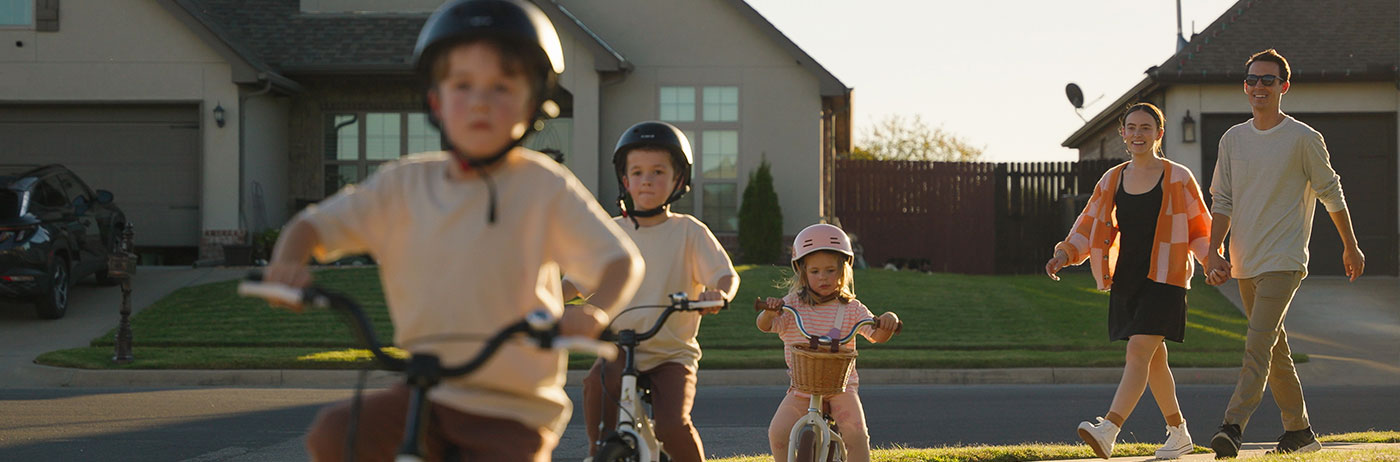 parents walking in neighborhood with their kids on bikes