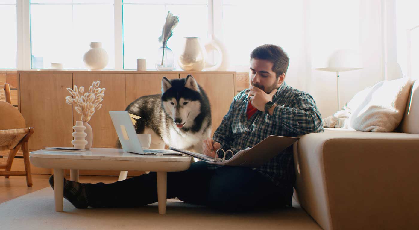 man working on laptop with dog watching
