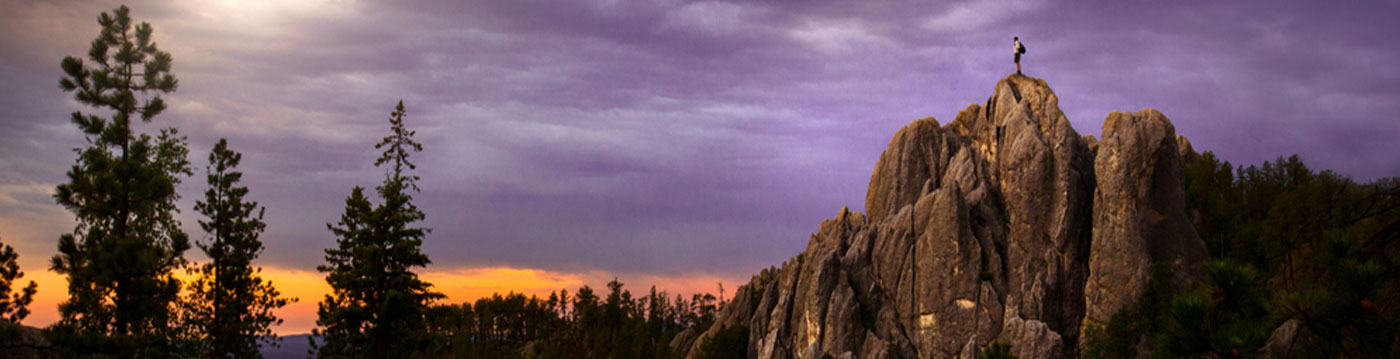 climber on top of black hills rock outcropping