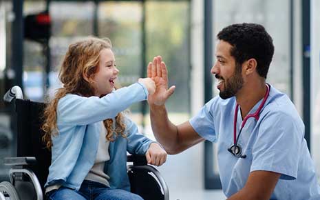 doctor giving high five to girl in wheelchair