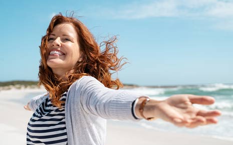 smiling woman in sweater at beach