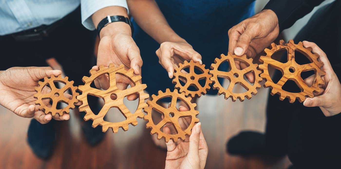 wooden cogs held together by many hands