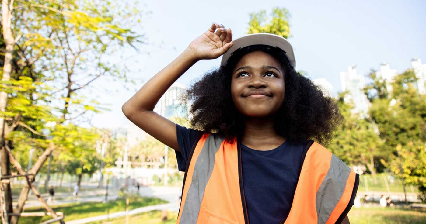 smiling young person in orange safety vest and hard hat