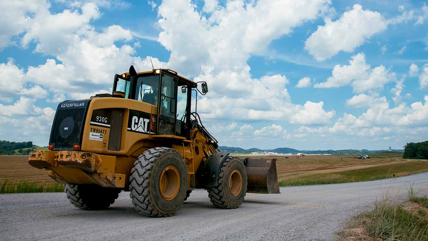 caterpillar wheel loader on road alongside industrial park open land
