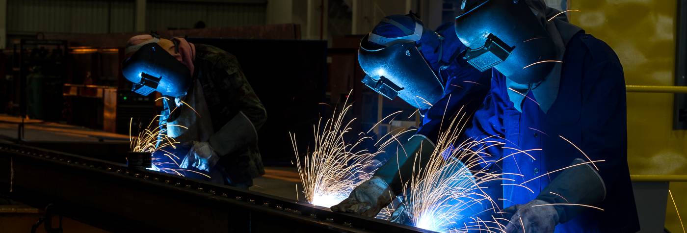 three workers with protective masks welding metal
