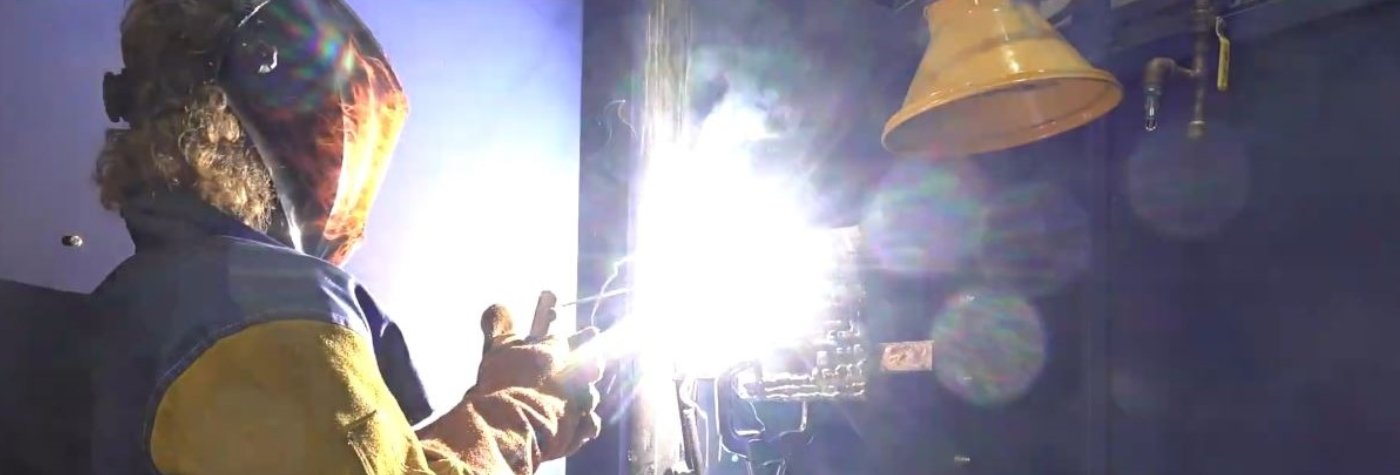 person wearing helmet prepares metal product