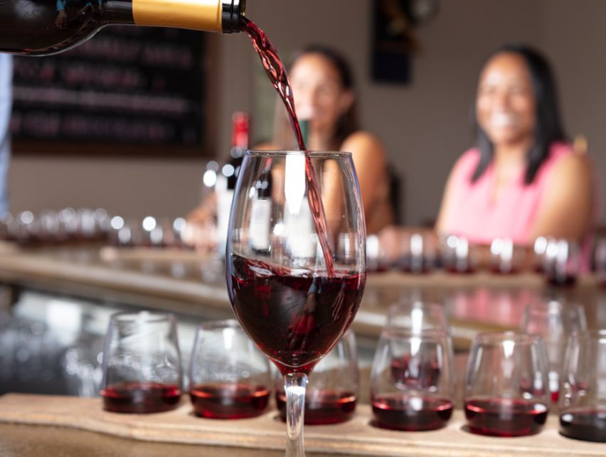 wine pouring a wine glass with two people and more glasses in the background