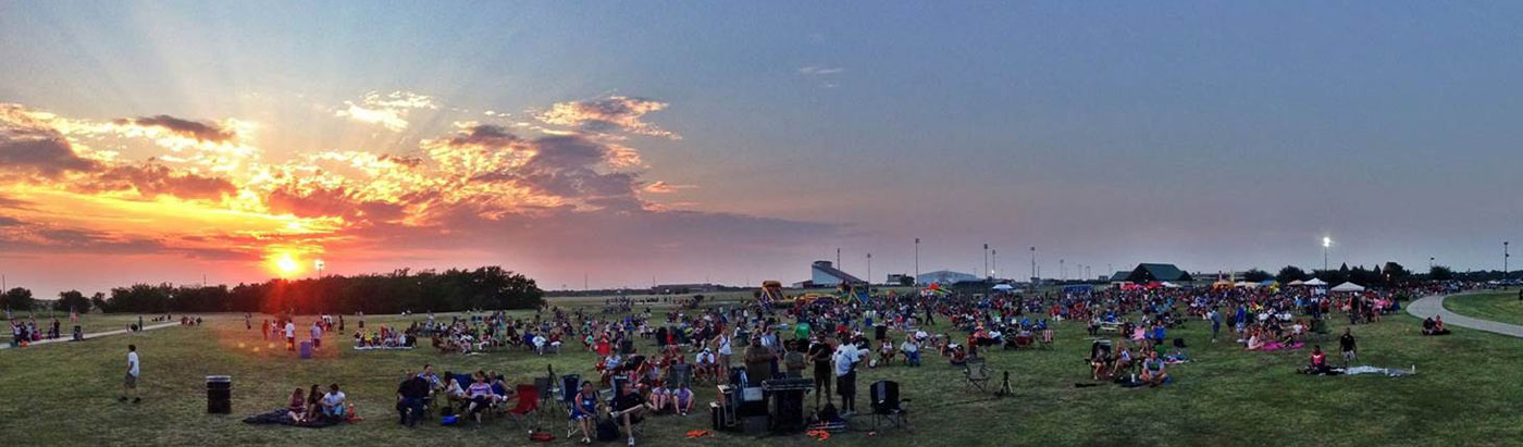 People sitting on the grass at sunset in Greenville, TX