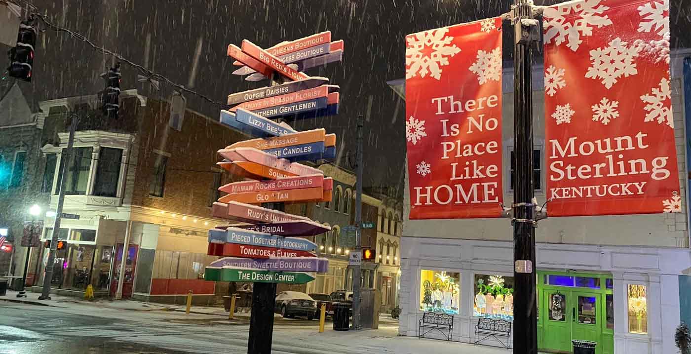 Snowfall in downtown Mt. Sterling, KY with holiday banner that says "There is no place like Mount Sterling"