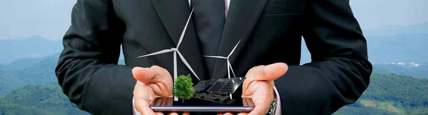 Ecology concept hands holding businessman on a smartphone with a tree and wind turbines