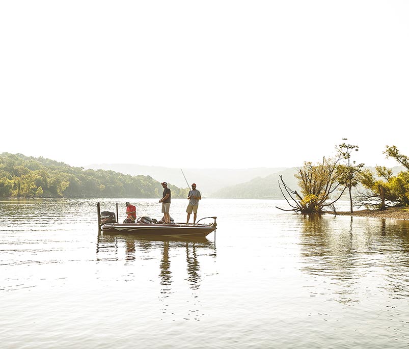 three men fishing from their boat on a beautiful lake