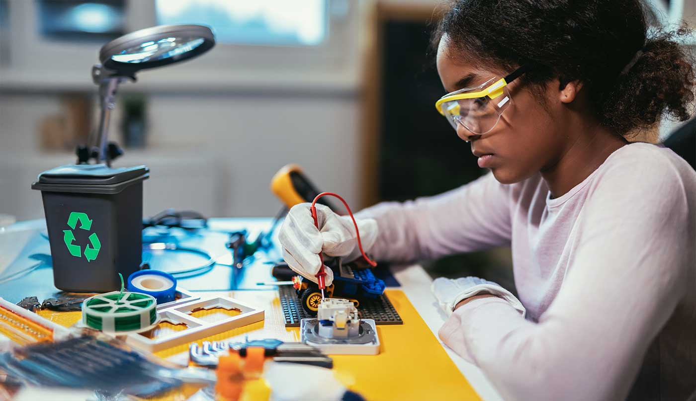 schoolgirl sodering an electronic project in her science robotics club