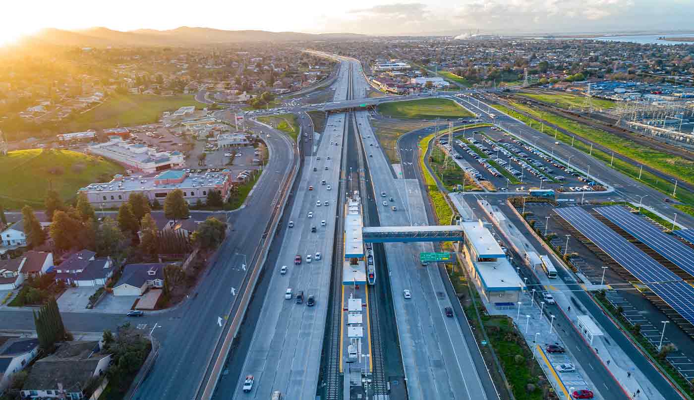 Aerial drone view of Antioch BART station, surrounding solar parking lot, and Highway 4 traffic during sunset in Eastern Contra Costa County, CA