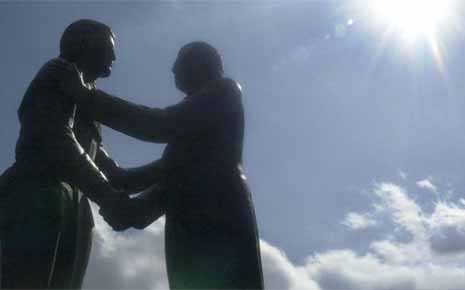 statue of two men shaking hands and clouds
