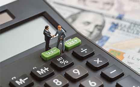 iniature people businessmen handshaking standing on TAX minus button on calculator