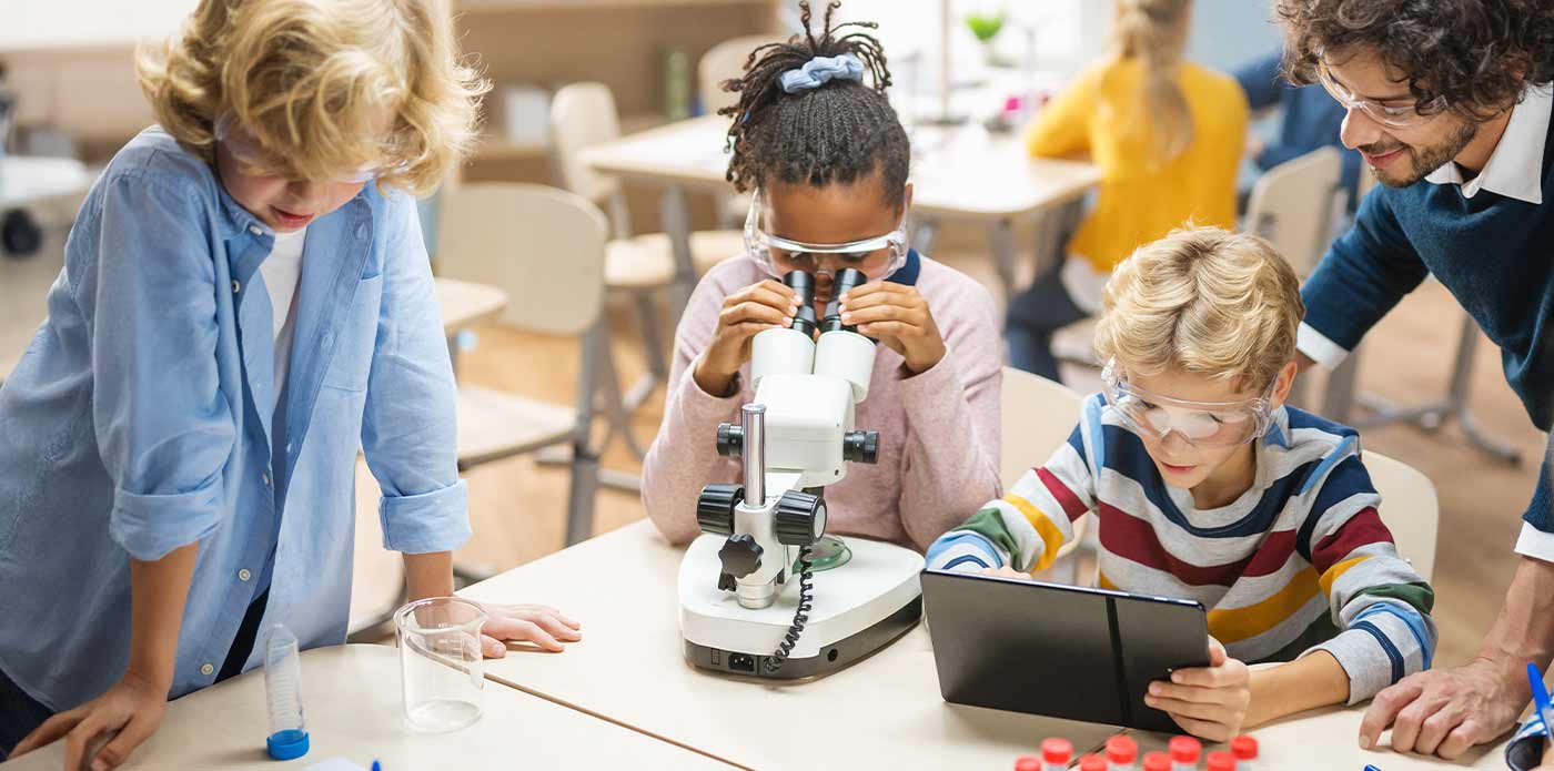 science teacher and students in classroom with microscope