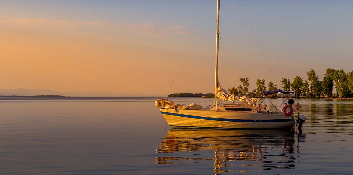 A sailboat at anchor in Plattsburgh Bay, NY at sunrise