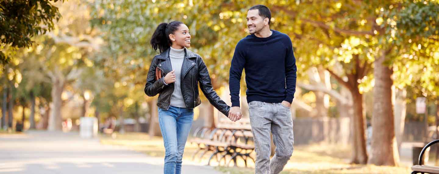 A couple walking through a park, surrounded by trees