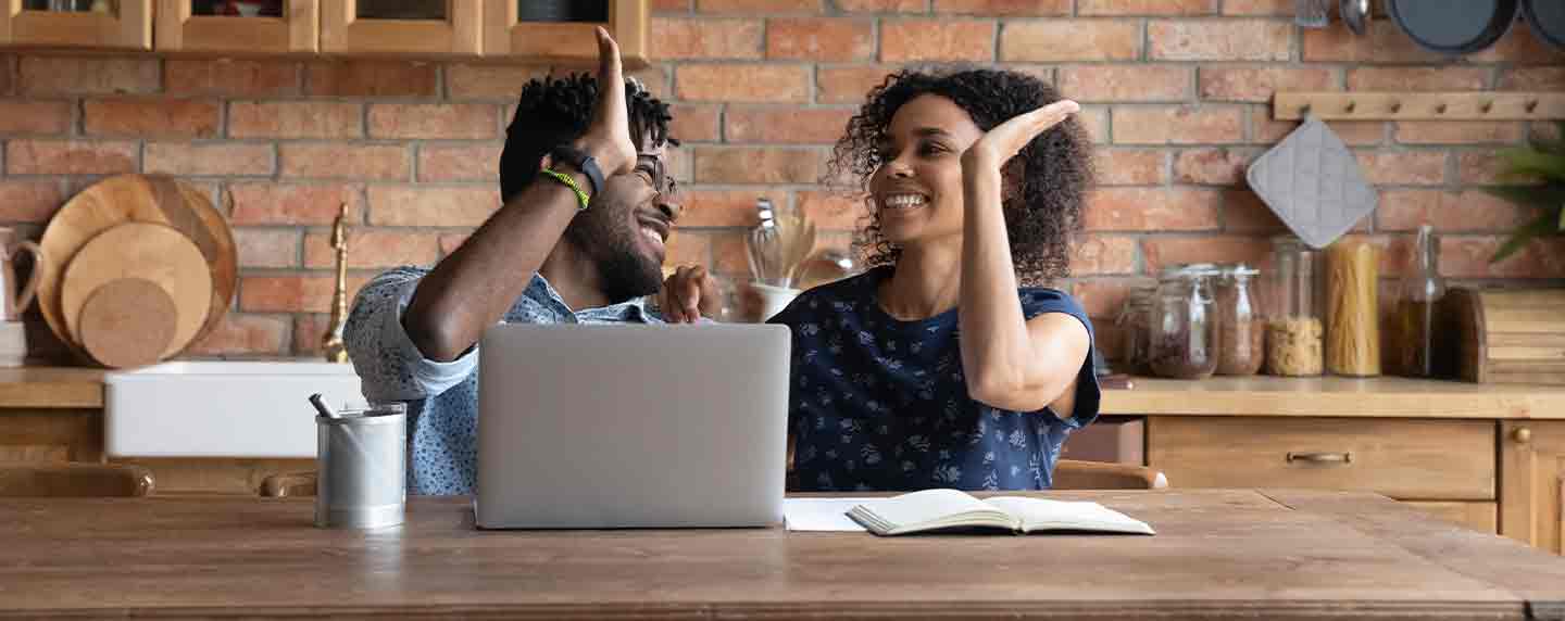 Two people high fiving in front of their laptop
