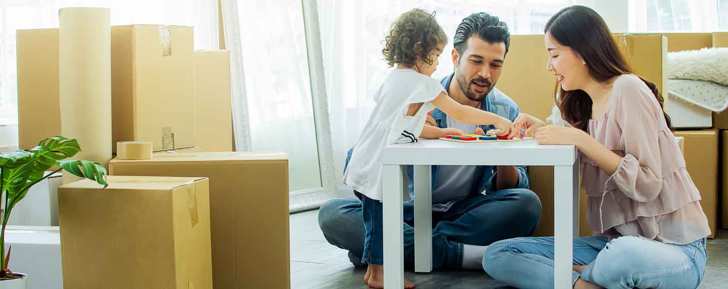 A couple and their young child work on a puzzle while moving into a home