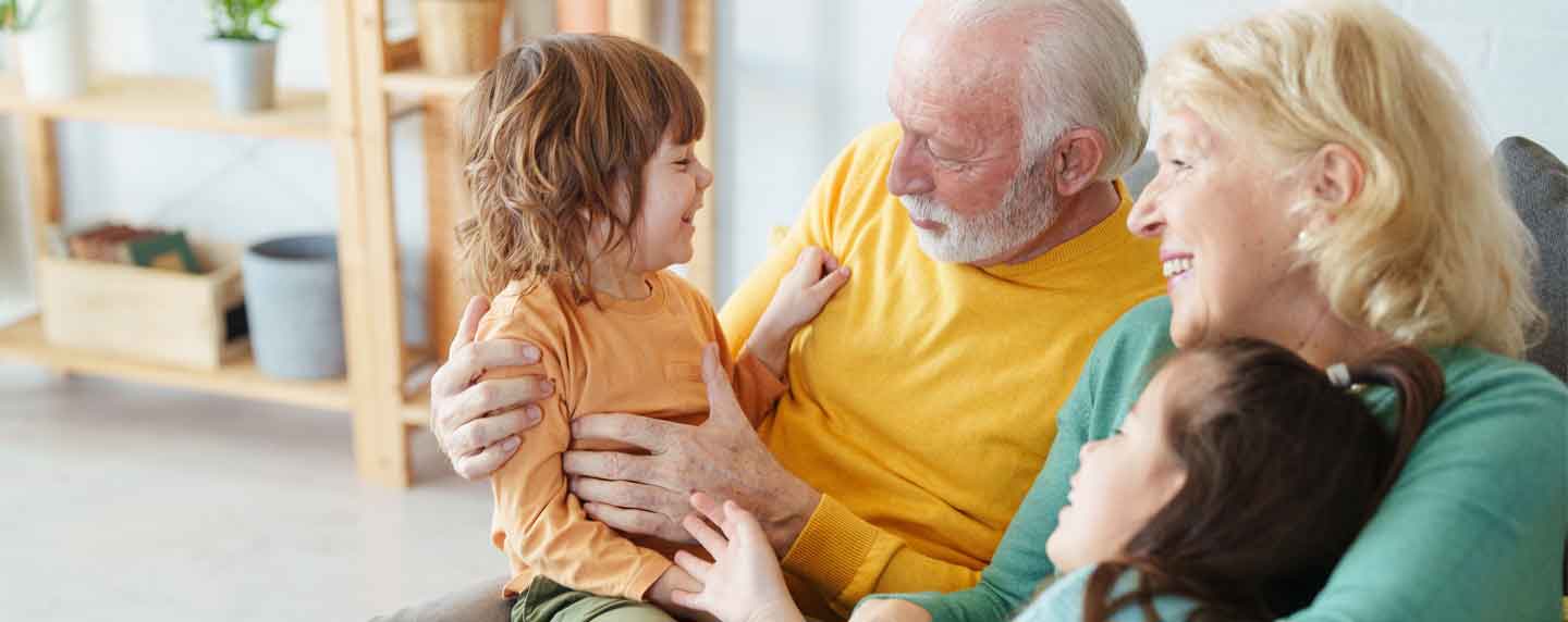 An elderly couple sits with grandkids