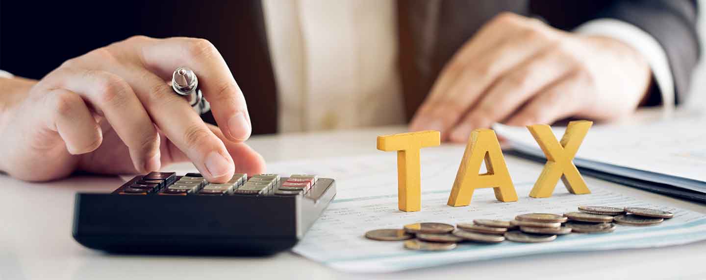 The word tax in front of coins and next to a calculator