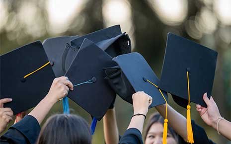 A group of people are holding up their graduation caps