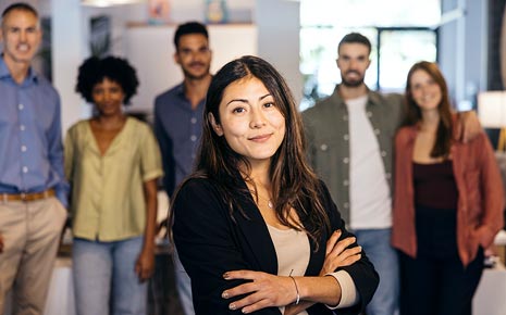 A woman in the forefront and a group of diverse people standing in the background